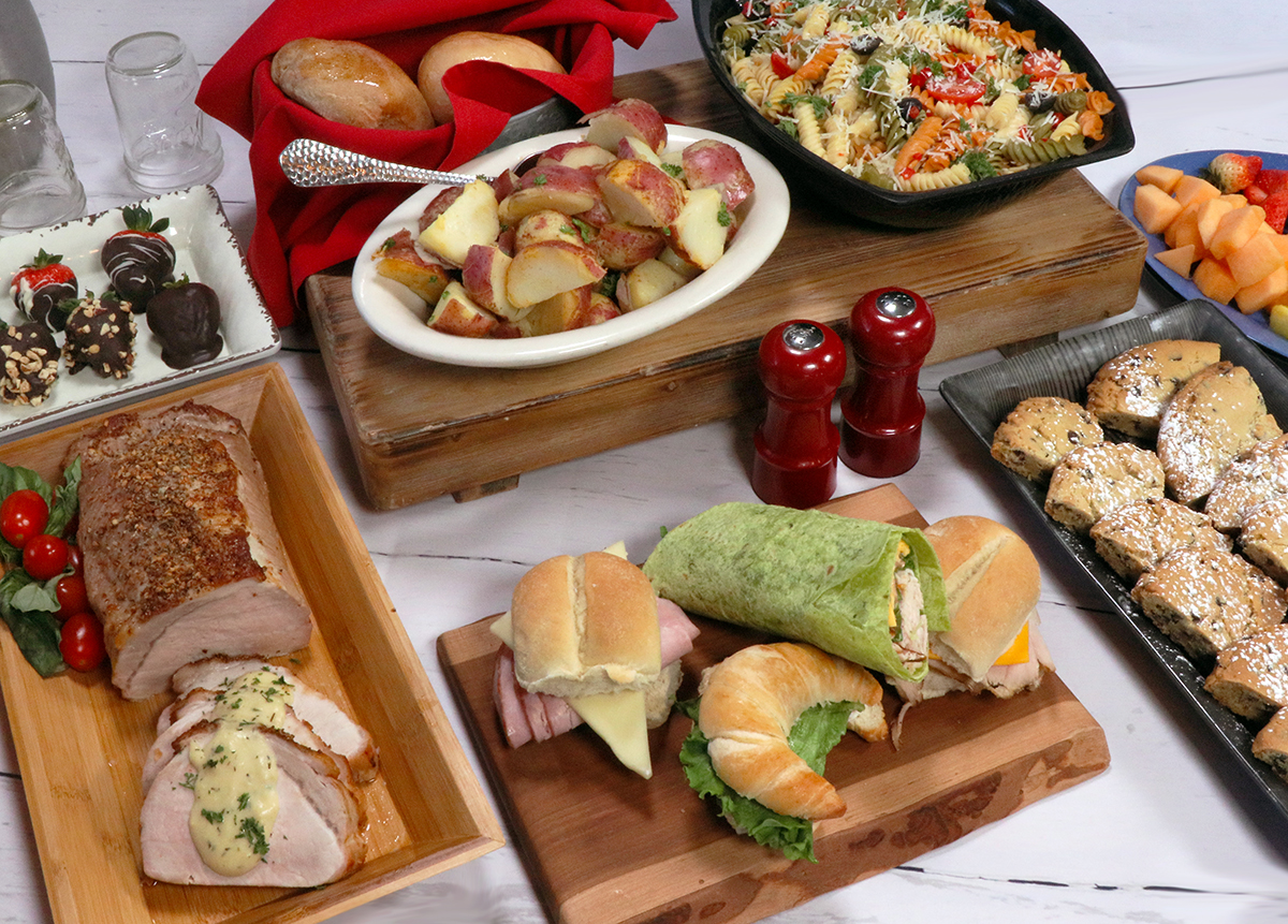 table spread with food, wraps, fruit, pasta, cookie bars, pork loin, potatoes, and chocolate covered strawberries at Machine Shed