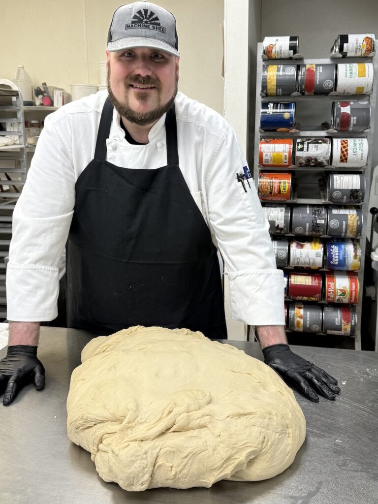 Machine Shed chef standing in front of a table with a massive pile of Cinnamon Roll dough